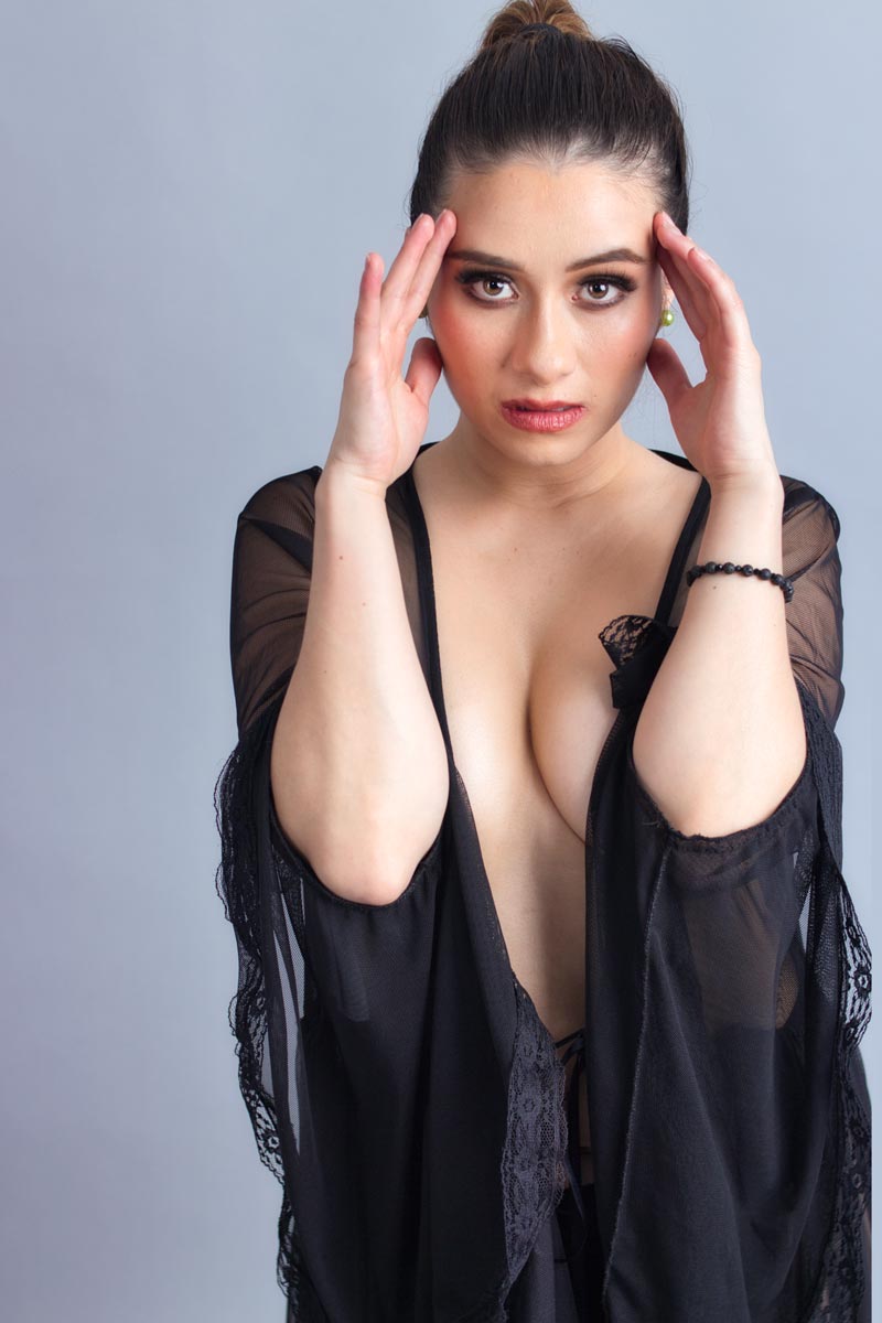 Retrato de Flor Jesarelt con manos enmarcando el rostro, bata negra semitransparente, sesión de moda editorial en estudio, Ciudad de México, fotografía por Josué Palma