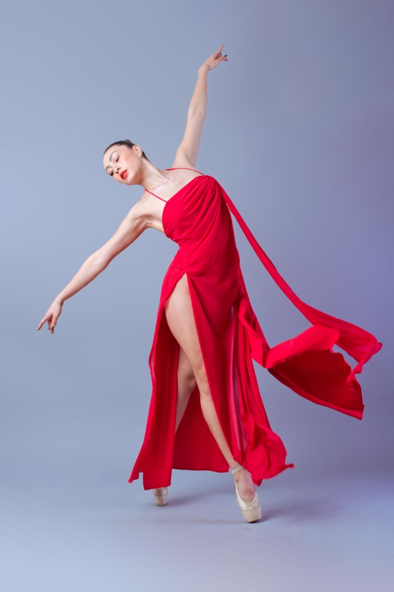 Llublyn Ponce con vestido rojo satinado en pose de arabesque, brazo elevado y ojos cerrados, sesión de moda editorial en estudio, Ciudad de México, fotografía por Josué Palma