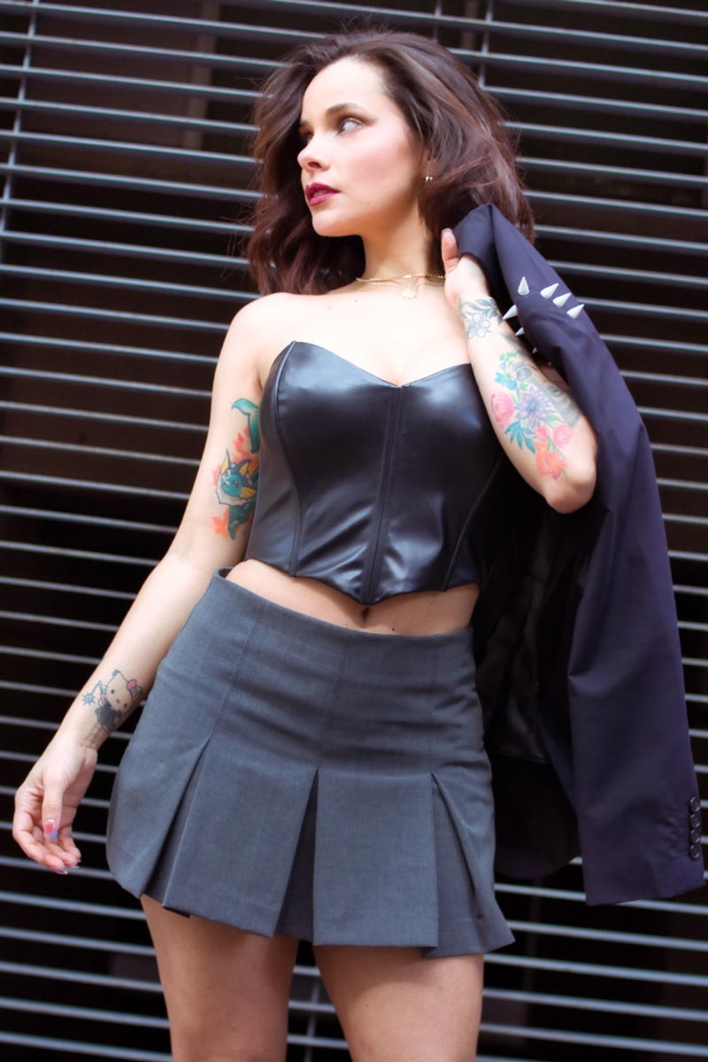 Sarita Souza con corset negro y falda plisada gris, blazer sobre el hombro, mirada hacia atrás, sesión editorial fashion urbana CDMX, fotografía por Josué Palma