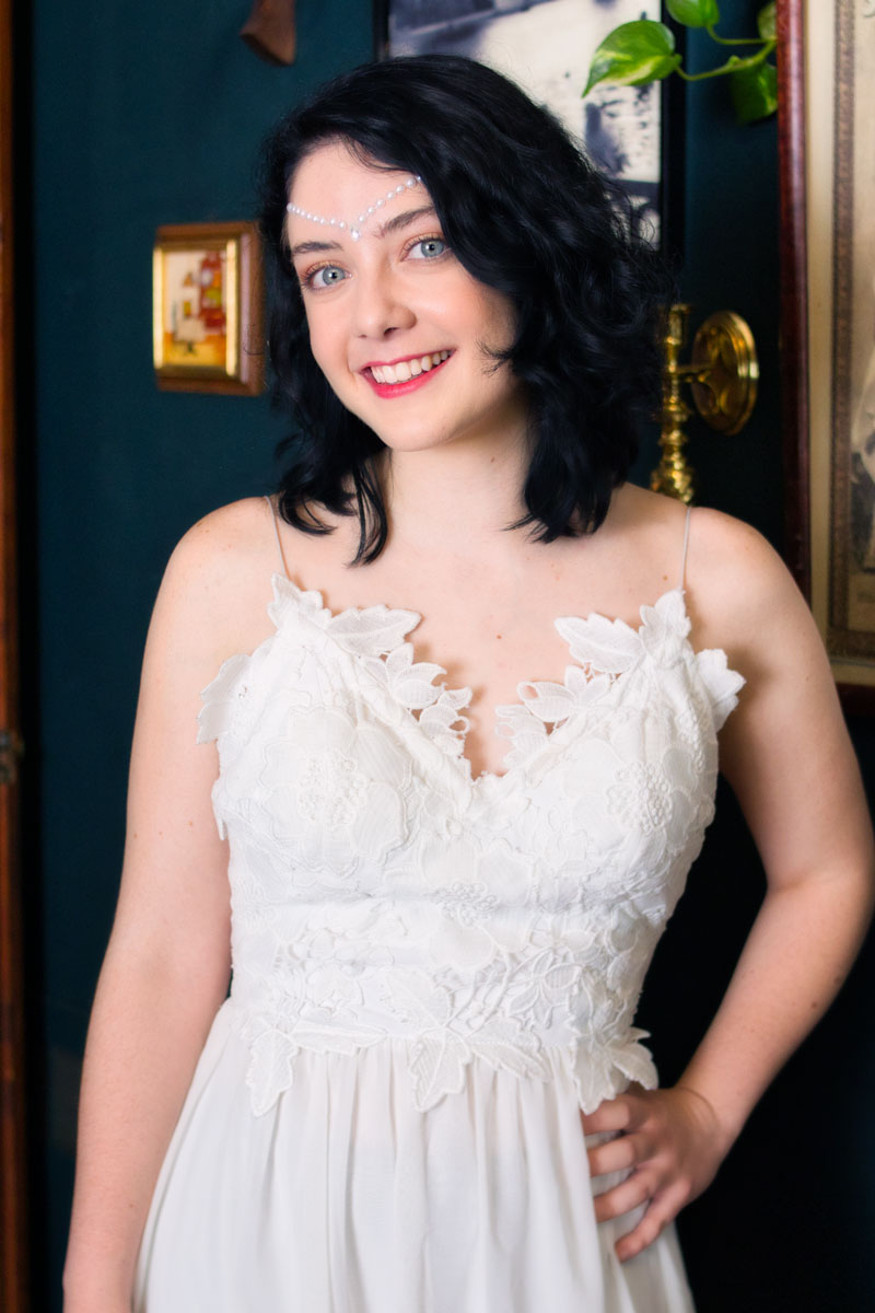 Retrato de Victoria Daninisa con vestido blanco de encaje y tocado de perlas, sonriendo, fondo de pared verde azulado, sesión editorial CDMX, fotografía por Josué Palma